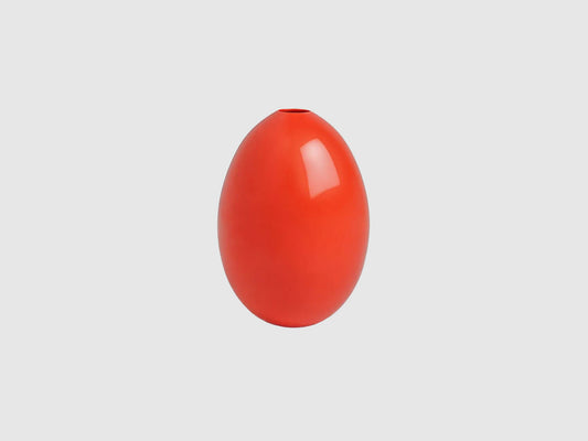 Kleine, eiförmige Vase aus glänzend korallenrotem Porzellan vor hellem Hintergrund.
Small egg-shaped vase in glossy coral red porcelain against a light background.