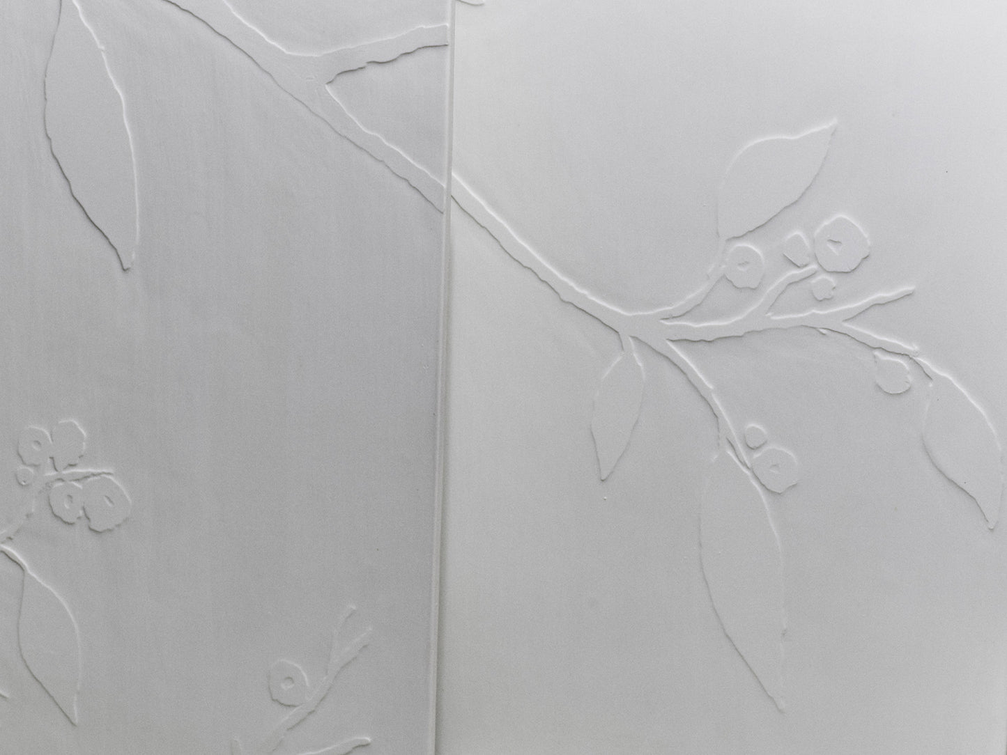 Nahaufnahme zweier Kirschblüten-Fliesen mit ineinanderlaufendem Astrelief.
Close-up of two cherry blossom tiles with an interlocking branch relief.