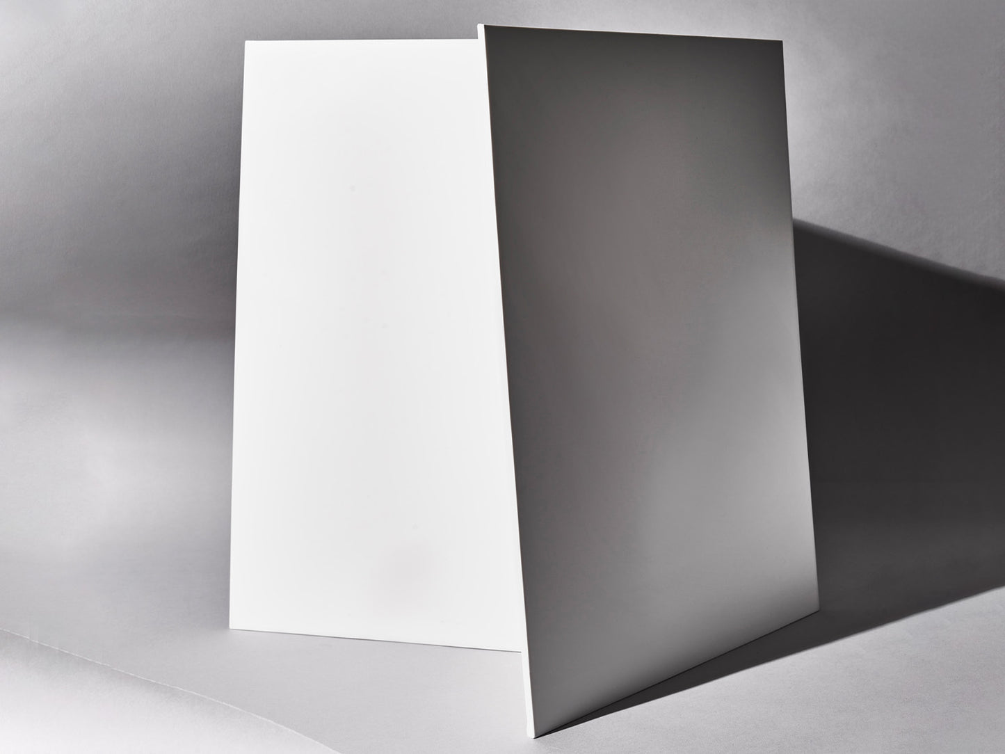 Zwei weiße Fliesen lehnen gegeneinander in Studioumgebung.
Two whote tiles leaning against each other in studio setting.