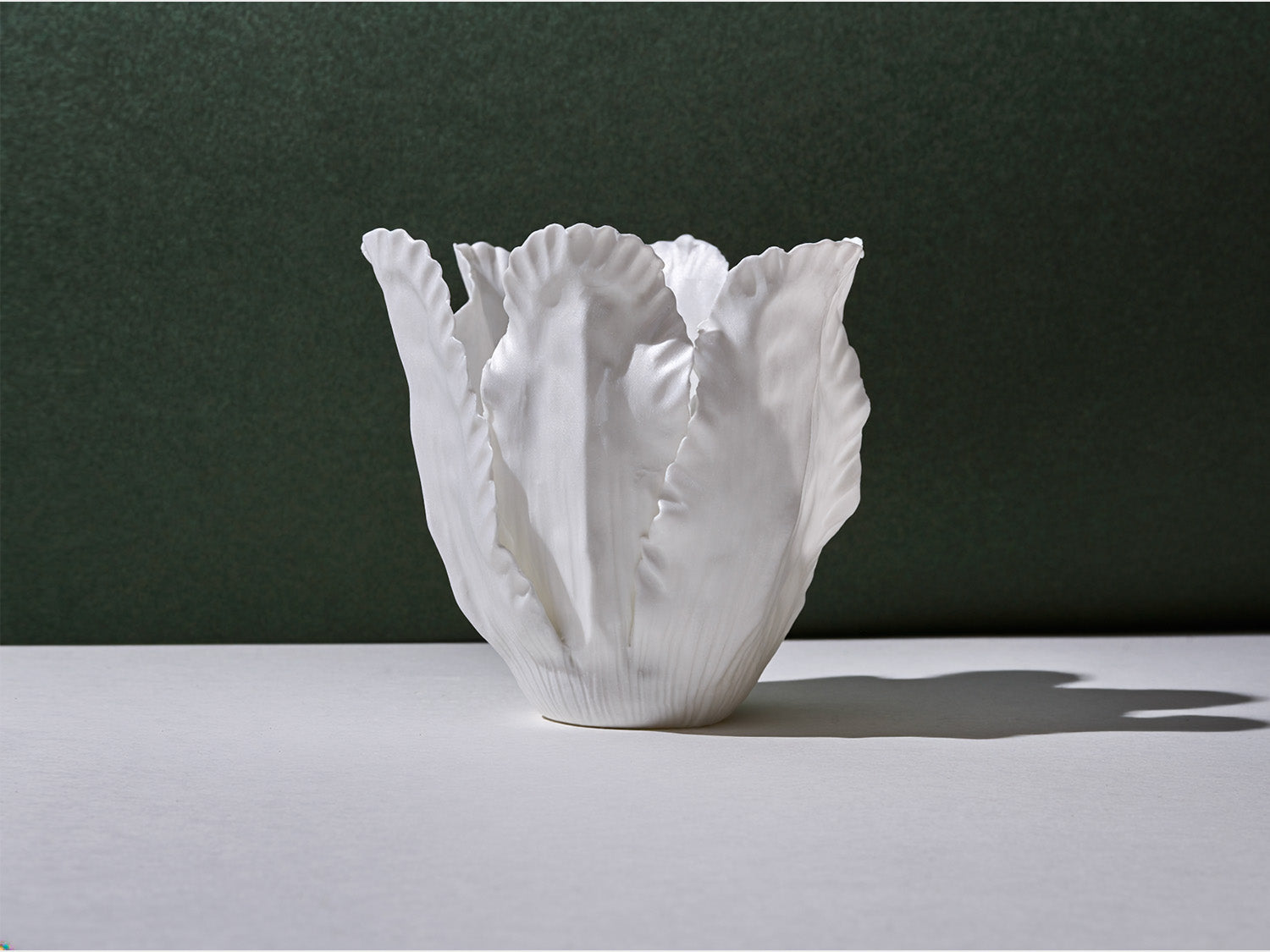 Unbeleuchtetes Biskuitporzellan-Windlicht in Blütenform; weiße, gerippte Blätter mit fein gewelltem Rand auf neutralem Hintergrund.


Unlit bisque-porcelain tea-light shaped like a flower; white, ribbed leaves with softly ruffled edges on a neutral background.