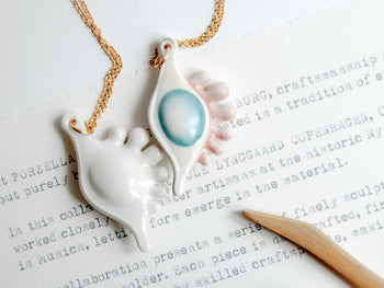 Porzellananhänger in organischer Form mit pastellfarbenem Relief und Goldkette aus der Kooperation von Nymphenburg und Ole Lynggaard Copenhagen.

Organic-shaped porcelain pendant with pastel relief and gold chain from the collaboration between Nymphenburg and Ole Lynggaard Copenhagen.